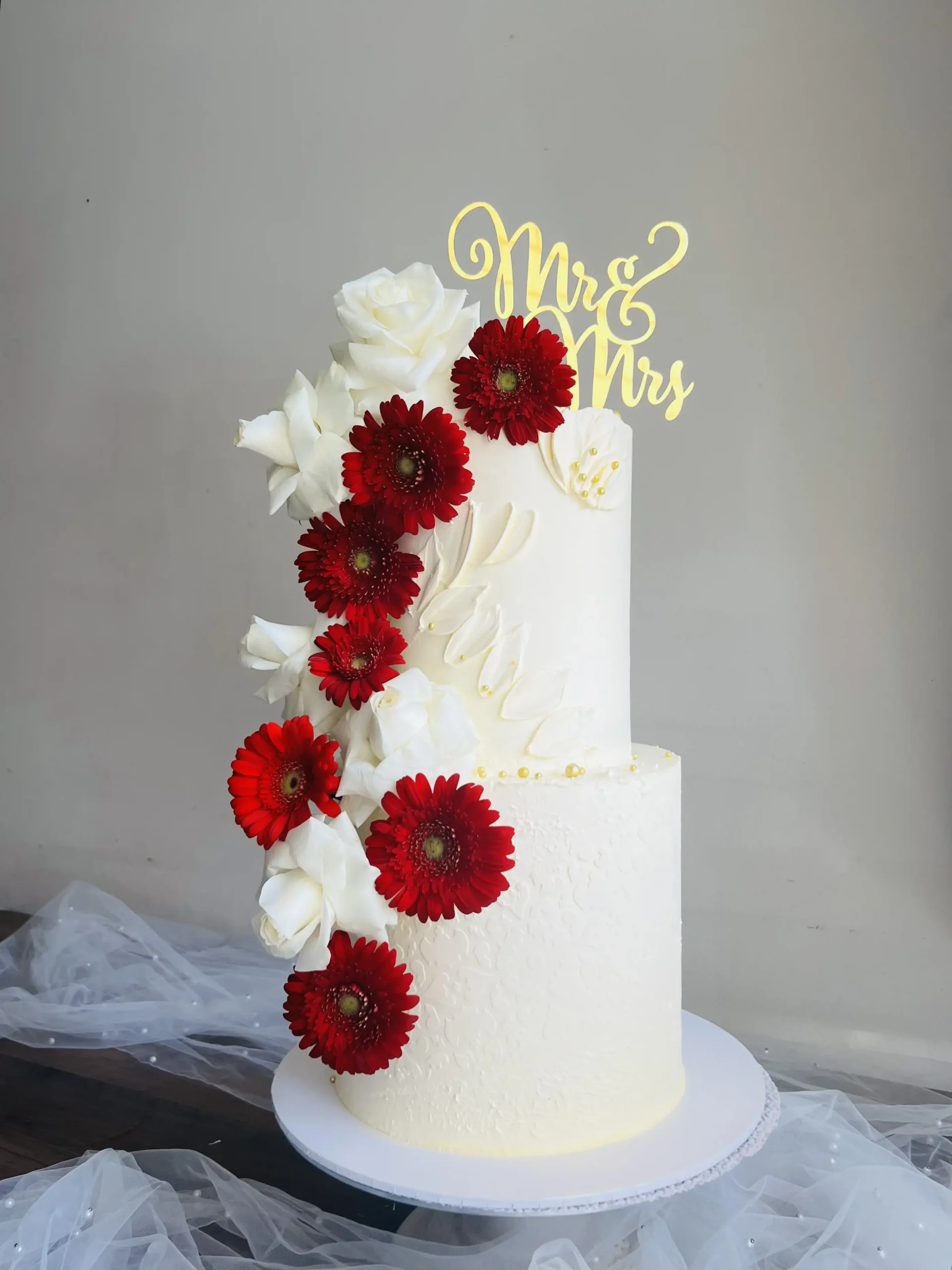 2 tier white wedding cake with red flowers.